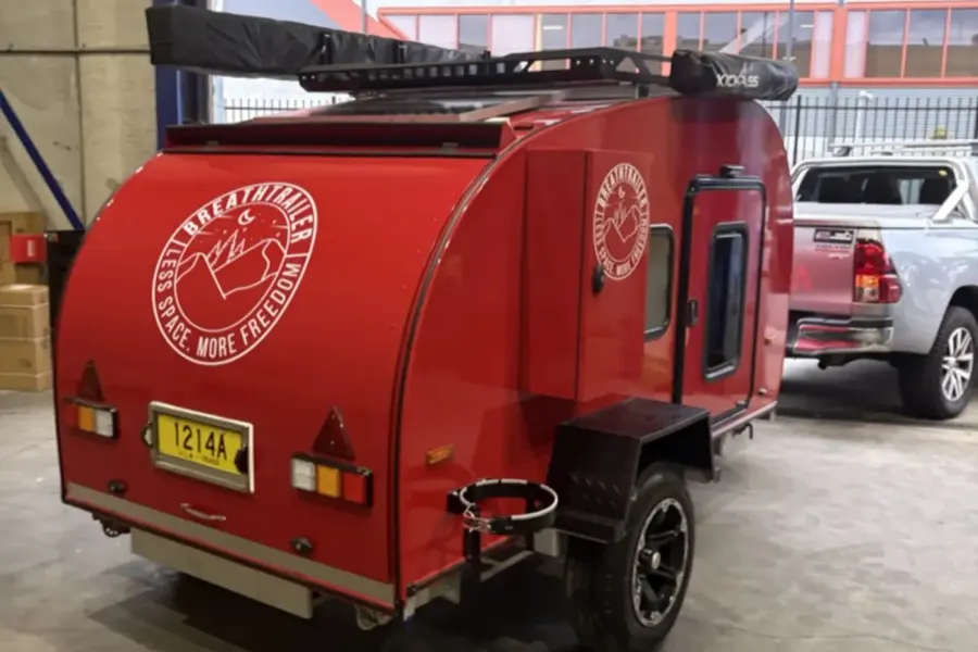 Breath Ultra in red from the rear with Breathtrailer logo, roof rack, awning and number plate