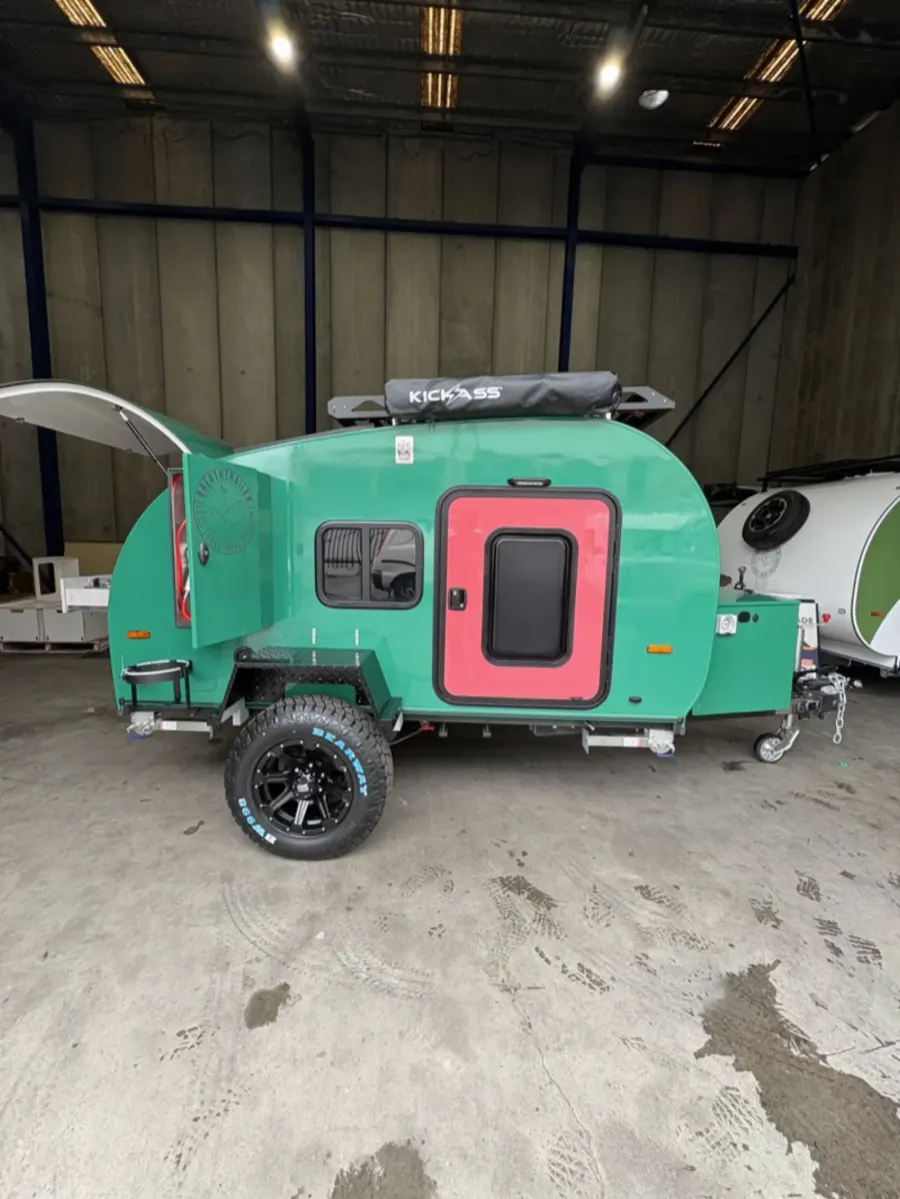 Breath Ultra in green with red door, roof rack, rolled awning and rear hatch raised, side profile