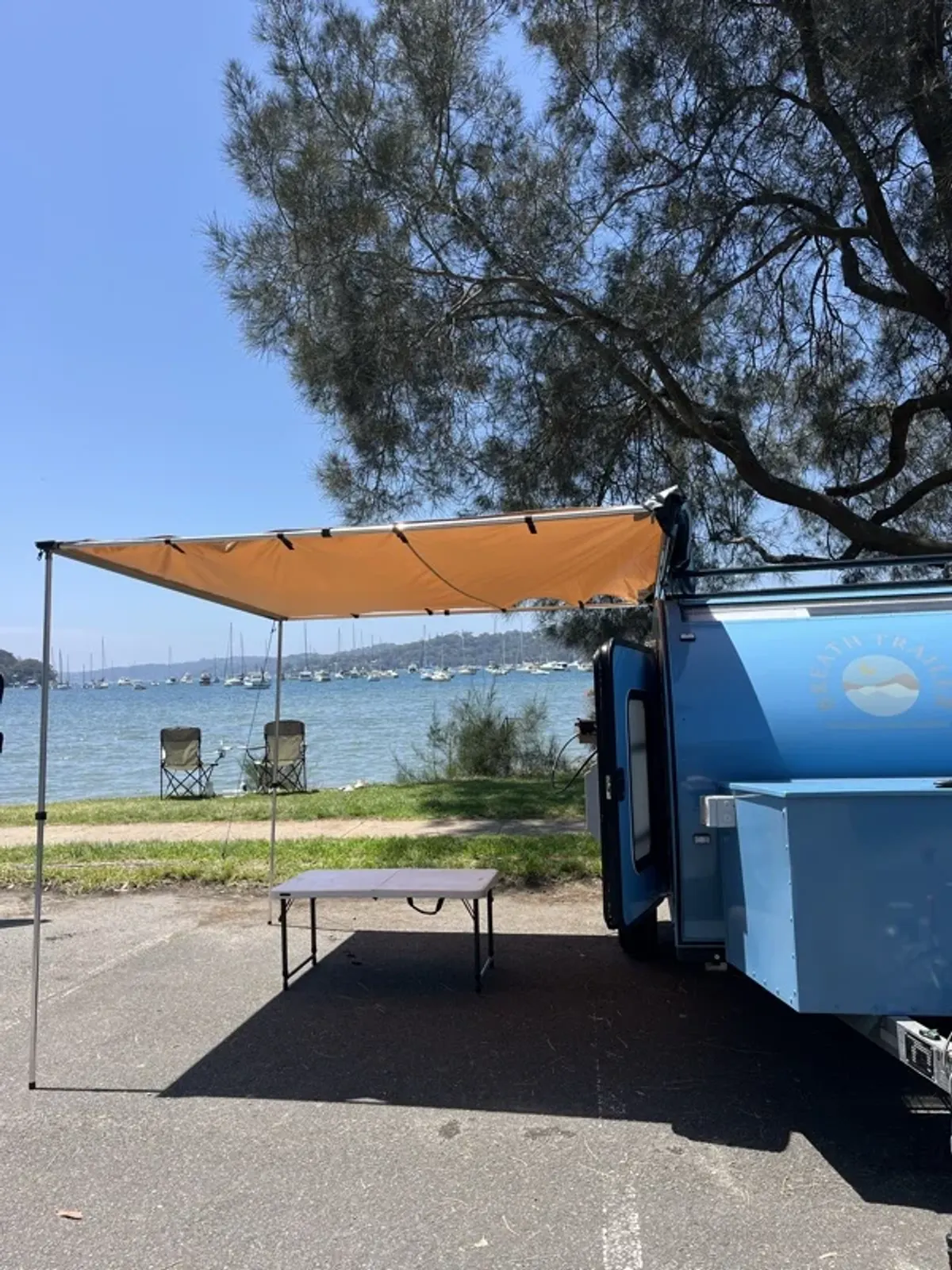 A blue Plus at camp with its optional awning open