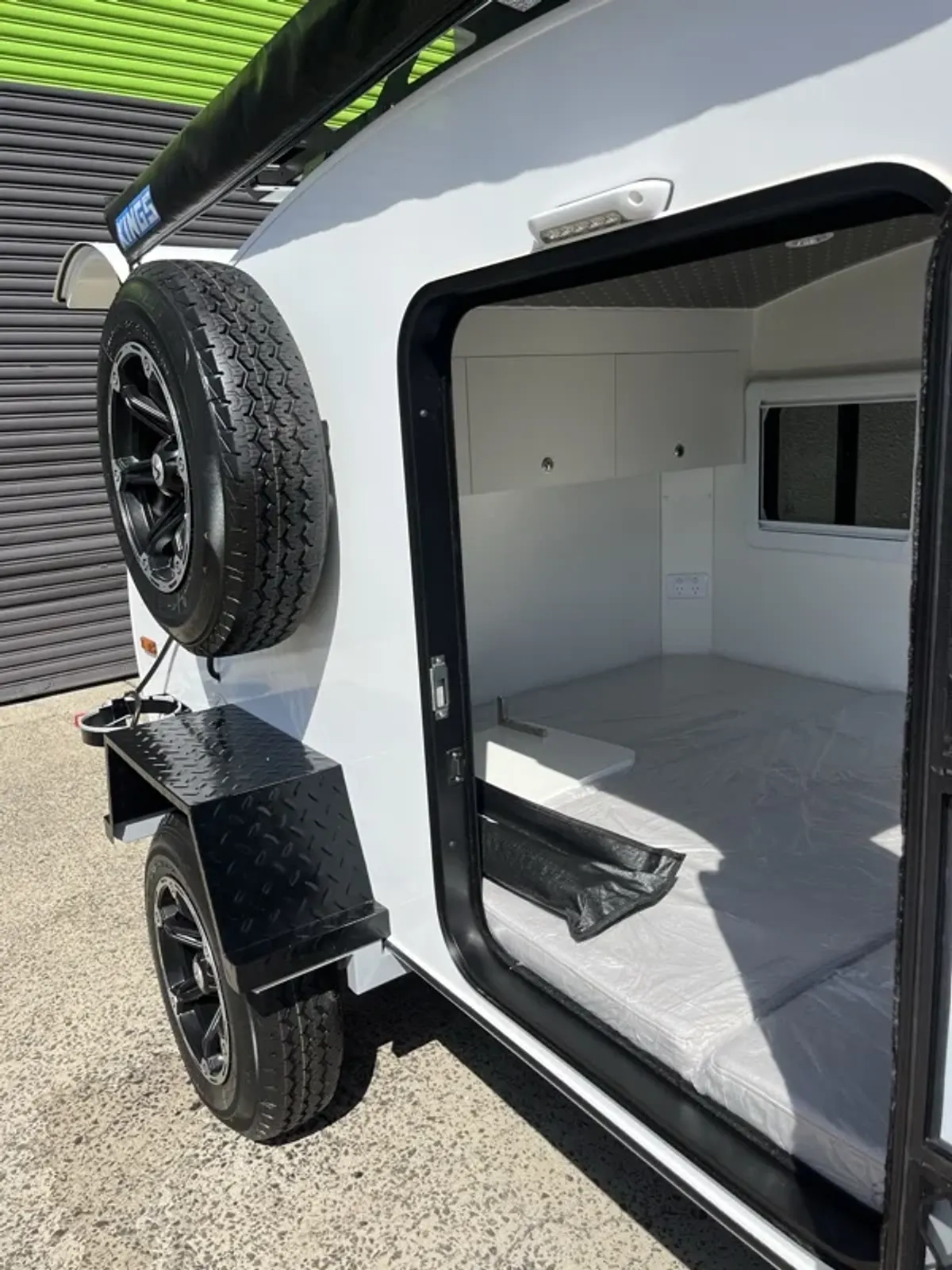 Fold-out table beside the spare tyre on a white Plus with its door open