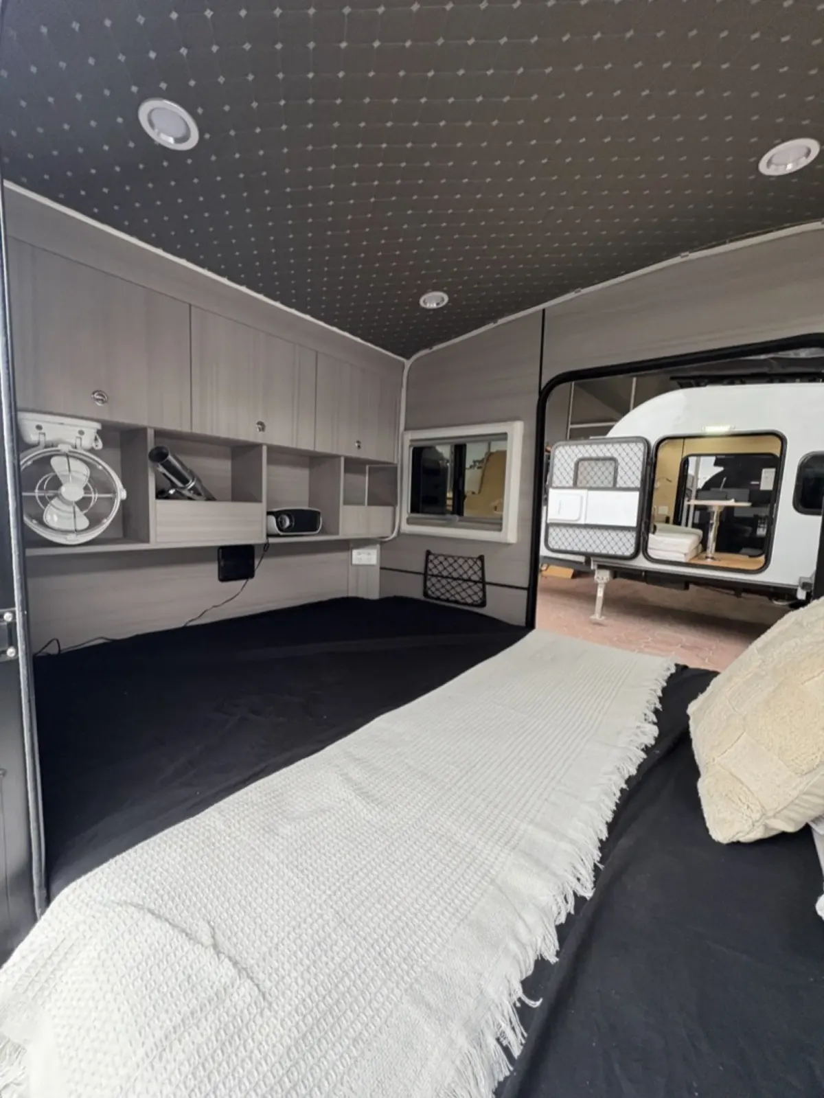 Breath Ultra sleeping cabin with a made bed, white throw, fan and overhead storage