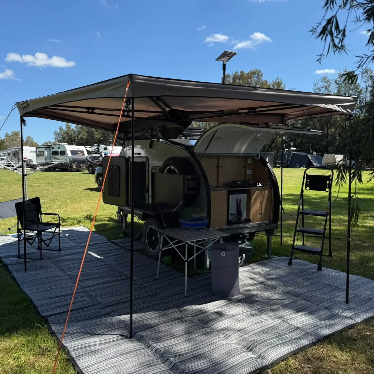 Ultra at a wooded campsite beneath its open awning